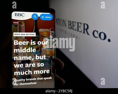 Personne tenant un smartphone avec la page Web de la brasserie américaine Boston Beer Company sur l'écran devant le logo. Concentrez-vous sur le centre de l'écran du téléphone. Banque D'Images