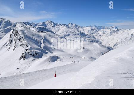 Skieurs et snowboarders descendant les pistes dans la station de ski des Menuires. Activités de sports d'hiver surplombant les montagnes enneigées dans les trois vallées. Banque D'Images