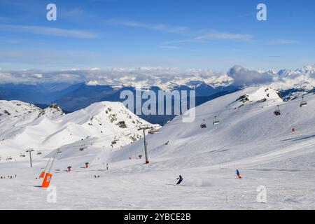 Skieurs et snowboarders descendant les pistes dans la station de ski des Menuires. Activités de sports d'hiver surplombant les montagnes enneigées dans les trois vallées. Banque D'Images