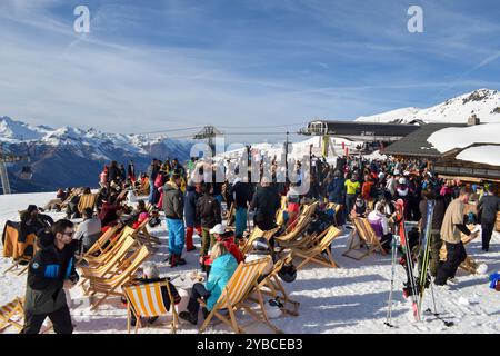 Les Menuires - 13 mars 2024 : Apres ski party par une piste de ski active dans la station de ski française les Menuires. Skieurs buvant à côté des montagnes enneigées. Banque D'Images