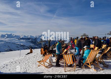 Les Menuires - 13 mars 2024 : Apres ski party par une piste de ski active dans la station de ski française les Menuires. Skieurs buvant à côté des montagnes enneigées. Banque D'Images