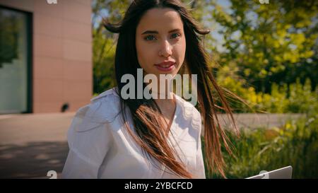 Souriant femme employée femme caucasienne étudiante travaillant à distance en ligne sur ordinateur portable naviguant sur le réseau social sur l'immeuble de bureaux de rue réussi Banque D'Images