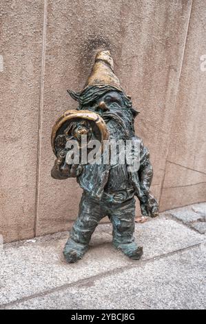 Des statues de gnome en bronze se dressent sur une rue pavée, mettant en valeur l'art fantaisiste dans un cadre urbain public. L'artisanat détaillé ajoute charme et char Banque D'Images