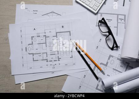 Différents dessins architecturaux, calculatrice, verres et crayons sur table en bois, vue de dessus Banque D'Images
