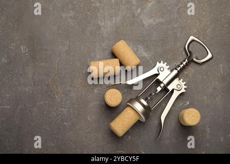 Tire-bouchon à ailes et bouchons sur table grise, pose à plat. Espace pour le texte Banque D'Images