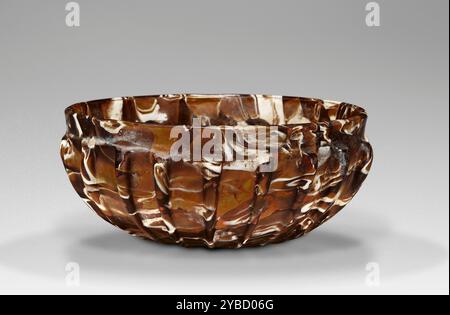 Bol nervuré, 25 B.C.-A.D. 50. Informations supplémentaires : le fabricant inconnu a probablement voulu ce bol nervuré de marbrures brunes et blanches pour imiter l'apparence d'un bol d'agate. Les récipients sculptés dans la pierre semi-précieuse étaient un article de luxe à la mode et cher dans la Rome du premier siècle. Les bols en verre qui ressemblaient à ceux en agate étaient beaucoup moins chers à produire et répondaient à la demande accrue pour l'aspect de la pierre. Les petits bols avec des nervures verticales à l'extérieur sont l'une des formes les plus courantes de récipients en verre romains primitifs. La forme est originaire de bols en verre taillé de la période hellénistique, mais le te Banque D'Images