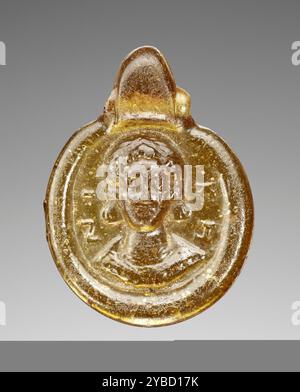 Pendentif, vie-VIIe siècle. Informations supplémentaires : verre jaunâtre de couleur ambre portant un buste portrait frontal dans le style byzantin impérial. Il semble être une femme portant une couronne avec pendilia. Inscrit dans le champ : ni à gauche ; KH à droite. Banque D'Images