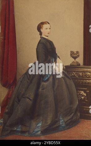 S.A.R. la Princesse de Galles, 1862-1864. Carte-de-visite représentant la princesse de Galles debout en profil trois-quarts à côté d'un buffet en bois. Banque D'Images