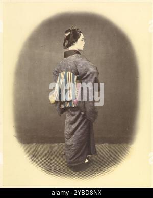 Jeune dame aristocratique, vers 1863-1868. Une femme se tient dos à la caméra en profil 3/4. Elle est habillée d'un kimono avec un obi rayé. Banque D'Images