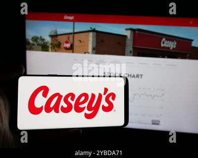 Personne tenant un smartphone avec le logo de la société américaine Casey's General Stores Inc sur l'écran en face du site Web. Concentrez-vous sur l'affichage du téléphone. Banque D'Images