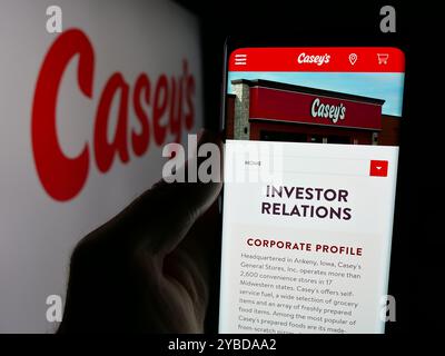 Personne tenant le téléphone portable avec la page Web de la société américaine Casey's General Stores Inc sur l'écran devant le logo. Concentrez-vous sur le centre de l'écran du téléphone. Banque D'Images