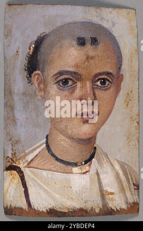 Portrait de momie d'un jeune, A.D. 150-200. Informations supplémentaires : un taux élevé de mortalité infantile en Égypte romaine a encouragé la confiance dans les sorts magiques pour conjurer la maladie et les blessures. Pour cette raison, le garçon porte un petit récipient rond pour amulettes sur un collier noir Uni, peut-être en cuir. Sa tête a été presque complètement rasée pour présenter une seule mèche à l'arrière (avec clip doré) et deux petites touffes sur son front. Ce modèle est conforme aux pratiques des dévots de la déesse Isis, dont le fils le Dieu-enfant Horus était le modèle pour ce traitement capillaire. Banque D'Images