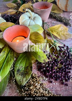 Arrangement d'automne confortable avec des bougies, de petites citrouilles et des baies, créant une pièce maîtresse chaleureuse et rustique parfaite pour les rassemblements d'automne ou Thanksgiving Banque D'Images