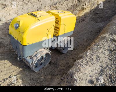 Compacteur de tranchée jaune télécommandé sur chantier de construction Banque D'Images