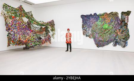 Londres, Royaume-Uni. 18 octobre 2024. L'artiste avec 'tenir sur Un peu plus longtemps', et 'sol fertile', les deux 2023. Saatchi Gallery présente les nouvelles œuvres de l’artiste textile nigérian Samuel Nnorom dans l’exposition personnelle « multitude ou minorité ». Les sculptures de Nnorom sont des métaphores visuelles réalisées à partir de chutes de tissu Ankara, tissu imprimé à la cire désormais synonyme de textiles africains. L'exposition sera ouverte du 19 octobre au 24 novembre 2024. Crédit : Imageplotter/Alamy Live News Banque D'Images