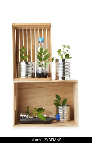 Concept de recyclage. Caisses en bois avec des plantes en bouteilles et canettes isolées sur blanc Banque D'Images