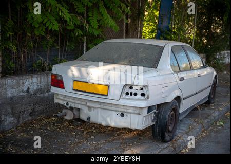 Voiture abandonnée et endommagée couverte de poussière et de feuilles Banque D'Images