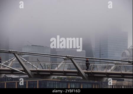 Londres, Royaume-Uni. 18 octobre 2024. Un homme marche le long du Millennium Bridge alors que le brouillard descend sur la City de Londres, le quartier financier de la capitale. Crédit : Vuk Valcic/Alamy Live News Banque D'Images