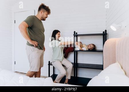 Heureux moment en famille à la maison : les parents profitent de moments ludiques avec leur enfant énergique à la maison Banque D'Images