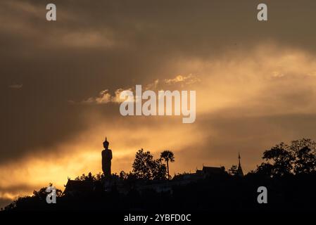 Chiang mai, Thaïlande. 18 octobre 2024. Les derniers rayons du soleil couchant disparaissent lentement au-dessus de l'horizon, avec le grand Bouddha debout en toile de fond à Wat Phra That Doi Kham. Les reflets du ciel au coucher du soleil affichent une variété de couleurs, telles que des teintes dorées et rouges, qui peuvent être vues chaque année en octobre avant l'arrivée de la saison d'hiver en Thaïlande. (Crédit image : © Pongmanat Tasiri/SOPA images via ZUMA Press Wire) USAGE ÉDITORIAL SEULEMENT! Non destiné à UN USAGE commercial ! Banque D'Images