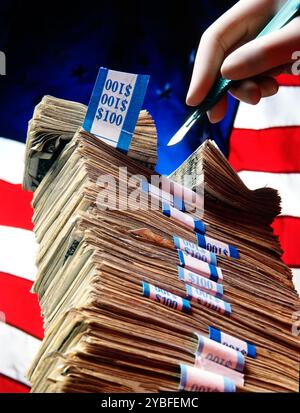 Une pile de billets de cent dollars Bing chirurgicalement coupés en deux avec un fond de drapeau américain représentant la réduction des coûts ou l'inflation en Amérique Banque D'Images