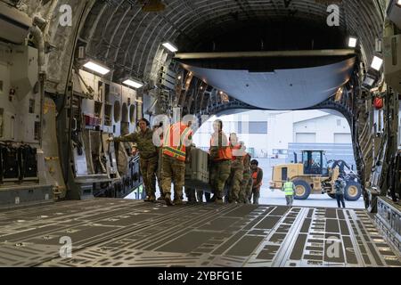 Les gardes nationaux de l'armée de l'Alaska, affectés au détachement 2, à la Charlie Company, au 3-140th Security and support Battalion, et les gardes nationaux de l'air de l'Alaska de l'autre côté de la 176th Wing transportent une caisse contenant quatre pales de rotor principal d'hélicoptère utilitaire léger UH-72A Lakota sur un C-17 Globemaster III à la base interarmées Elmendorf-Richardson, Alaska, octobre 11, 2024. Les aviateurs de l'AKANG affectés à la 176e Escadre ont transporté le détachement d'environ 20 soldats de l'AKARNG et deux hélicoptères UH-72A Lakota à la frontière sud-ouest pour soutenir la mission des douanes et de la protection des frontières des États-Unis. (Alaska National Guard phot Banque D'Images