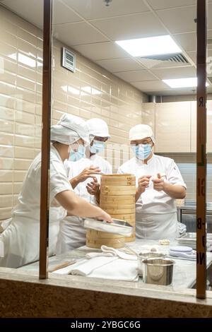Cuisiniers préparant des boulettes cuites à la vapeur dans le restaurant de cuisine taïwanaise DIN Tai Fung Singapour Banque D'Images