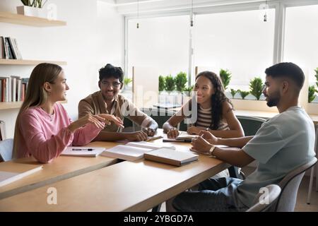 Heureux et divers camarades de classe d'université parlant à la table de la bibliothèque publique de l'université Banque D'Images