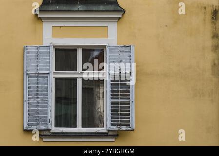 Vue rapprochée de l'ancienne fenêtre avec volets ouverts sur mur jaune Banque D'Images