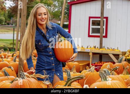 Une belle femme blonde européenne pics quelques citrouilles et fleurs pour les festivals d'automne à venir Banque D'Images