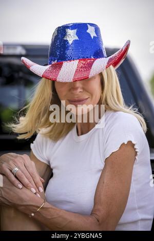 Une superbe mannequin mature rayonne de joie alors qu'elle célèbre le 4 juillet dans un chapeau de cow-boy rouge, blanc et bleu festif. Son sourire rayonne comme elle aime le Banque D'Images