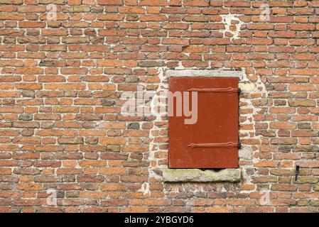 Ancienne forteresse mur avec une trappe en bois de couleur rouge Banque D'Images