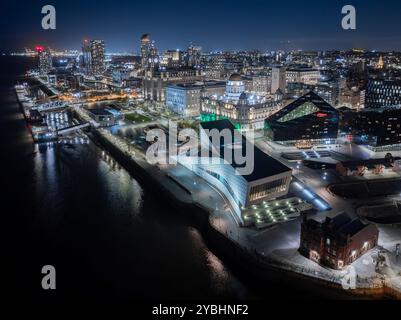 Vue aérienne du front de mer de Liverpool la nuit, avec Pier Head, les Three Graces et les bâtiments illuminés bordant la rivière Mersey. Banque D'Images