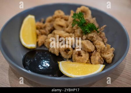 Photo rapprochée de calmars frits ou calamars avec citron servi dans l'assiette. Banque D'Images