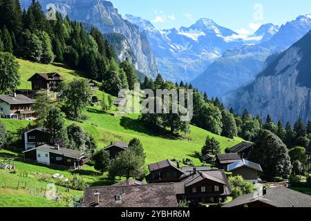 Chalets à flanc de colline près du village de Wengen au-dessus de la vallée de Lauterbrunnen avec le pic de montagne Breithorn (horizon central) dans les Alpes bernoises, SWI Banque D'Images