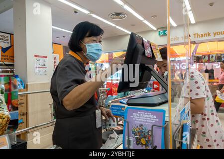 Une ouvrière caissière au supermarché FairPrice Singapour Banque D'Images