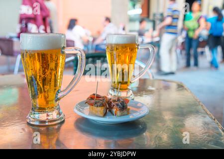 Apéritif espagnol : deux verres de bière avec une tapa sur une terrasse. Madrid, Espagne. Banque D'Images