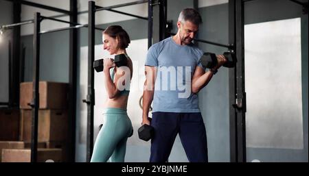 Couple de fitness faisant de l'exercice musculaire de musculation de musculation dans le gymnase Banque D'Images
