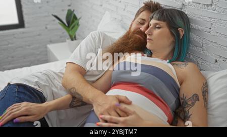 Femme enceinte dormant avec son partenaire dans une chambre confortable, embrassant son ventre avec amour et convivialité. Banque D'Images
