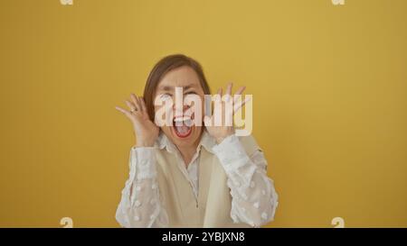 Femme mature avec les cheveux courts dans une blouse blanche ravie sur un fond jaune. Banque D'Images