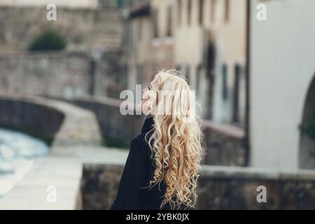 Jeune femme aux longs cheveux blonds explore joyeusement la charmante architecture italienne, admirant les vieux bâtiments et imprégnant la riche culture et l'histoire. URB Banque D'Images
