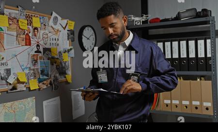 Un jeune homme concentré avec une barbe examine les preuves dans le bureau d'un détective de police encombré, suggérant une enquête et l'application de la loi. Banque D'Images