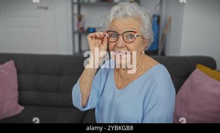 Femme âgée ajustant les lunettes à l'intérieur, mettant en valeur la positivité, le confort et le style dans un salon Banque D'Images