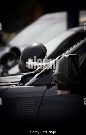 Gros plan du projecteur et du rétroviseur latéral avec lumière du marché secondaire sur Ford police Interceptor Utility, avec des voitures supplémentaires en arrière-plan Banque D'Images