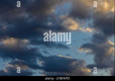 Alors que le jour passe à la nuit, des nuages tourbillonnants peignent le ciel, illuminé par les dernières notes de soleil. Cet écran captivant révèle la beauté Banque D'Images