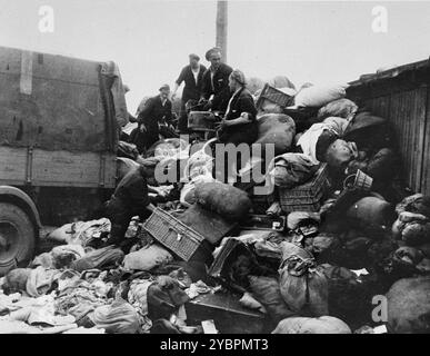 Les prisonniers des Aufräumungskommando (commandos d'ordre) déchargent les biens confisqués d'un transport de Juifs hongrois dans un entrepôt à Auschwitz. Les Juifs en Hongrie étaient relativement en sécurité jusqu'à ce qu'Hitler, craignant que la Hongrie cherche un accord avec les alliés, ordonne l'invasion du pays en mars 1944. Entre le 15 mai et le 9 juillet 1944, plus de 434 000 Juifs ont été déportés dans 147 trains, la plupart d'entre eux à Auschwitz, où environ 80% ont été gazés à leur arrivée. La progression rapide des expulsions a été rendue possible par une coopération étroite entre les autorités hongroises et allemandes. Banque D'Images