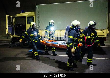 Jena, Allemagne. 20 octobre 2024. Dans un scénario d'embouteillage, les pompiers recherchent des personnes et les transportent vers le tube voisin. Les pompiers transportent un extra portant une cagoule respiratoire sur une civière. Exercice majeur dans le tunnel du Jagdberg sur l'A4 entre les jonctions Bucha et Jena-Göschwitz dans la nuit du 19 au 20 octobre 2024. Environ 200 pompiers, membres de la protection civile et de la police des autoroutes participent à l'exercice. Crédit : Jacob Schröter/dpa/Alamy Live News Banque D'Images