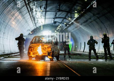 Jena, Allemagne. 20 octobre 2024. Dans un scénario d'urgence, une voiture est en feu dans le tunnel. Les pompiers s'entraînent à éteindre le véhicule. Exercice majeur dans le tunnel du Jagdberg sur l'A4 entre les jonctions Bucha et Jena-Göschwitz dans la nuit du 19 au 20 octobre 2024. Environ 200 pompiers, membres de la protection civile et de la police des autoroutes participent à l'exercice. Crédit : Jacob Schröter/dpa/Alamy Live News Banque D'Images