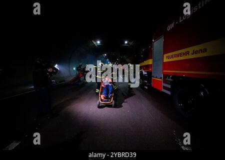 Jena, Allemagne. 20 octobre 2024. Dans un scénario d'embouteillage, les pompiers recherchent des personnes et les transportent vers le tube voisin. Un extra est transporté sur une civière. Exercice majeur dans le tunnel du Jagdberg sur l'A4 entre les jonctions Bucha et Jena-Göschwitz dans la nuit du 19 au 20 octobre 2024. Environ 200 pompiers, membres de la protection civile et de la police des autoroutes participent à l'exercice. Crédit : Jacob Schröter/dpa/Alamy Live News Banque D'Images