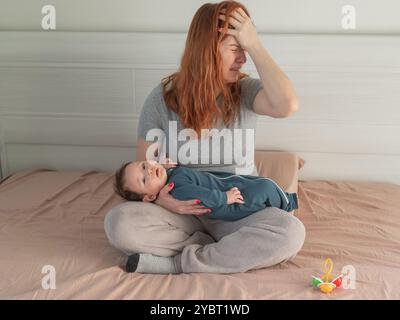 Une femme tient un enfant dans ses bras et pleure. Dépression du post-partum. Banque D'Images